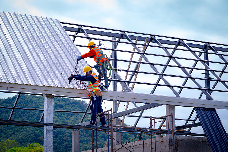 Roofer Worker In Protective Uniform Wear And Gloves, Using Air O two workers installing the roof